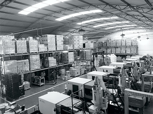 O galpão da fábrica, com as injetoras em linha e os copos embalados nas prateleiras